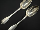 deux cuillères en argent posées sur une table l'une à côté de l'autre