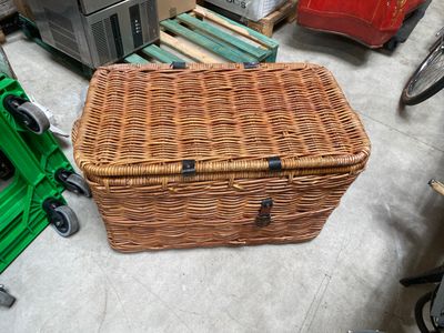 un panier en osier posé par terre à côté d'autres objets