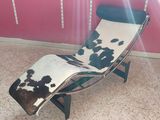a chair with a cow hide on it in front of a pink wall