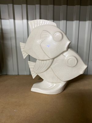 a white fish statue sitting on a table in front of a wall