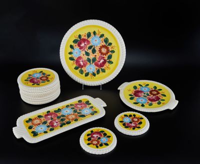 une assiette jaune décorée de fleurs, à côté d'un ensemble de dessous de verre et d'assiettes