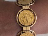 a gold bracelet with two gold coins on it