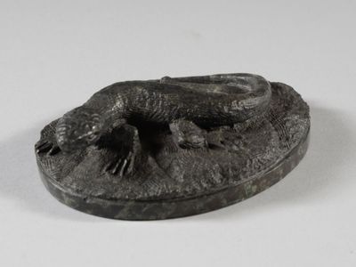une petite statue représentant un lézard, posée sur une assiette