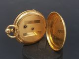 a gold pocket watch sitting on top of a black stand