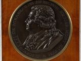 a close up of a medal on a wooden plaque with a white background