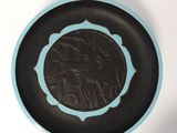 une assiette noire et bleue sur laquelle figure l'image d'un homme à cheval
