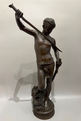 une statue antique en bronze représentant un homme tenant une lance
