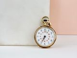 a small gold pocket watch sitting on a white table