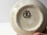 a person holding a white bowl with a black design