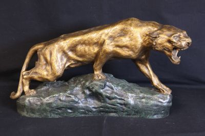bronze sculpture of a lion on a rock on a black background