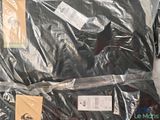 a black shirt wrapped in plastic on a white surface