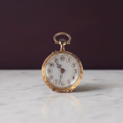 une montre de poche en or posée sur une table en marbre