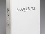« La reliure », un ouvrage écrit par l'auteur du roman, est présenté sur une surface grise