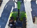 a small green tractor parked in a parking lot