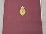 un livre rouge orné d'une médaille d'or