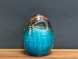 a blue and brown vase sitting on a wooden table
