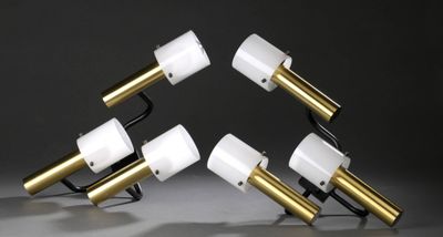 trois lampes blanches et dorées posées sur une table, sur fond noir