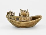 a small gold boat with people in it on a white surface