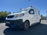 la camionnette blanche est garée sur le parking à côté des arbres