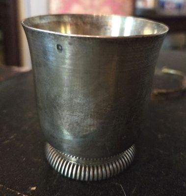 une coupe en argent posée sur une table, dont le bord est orné d'un anneau métallique