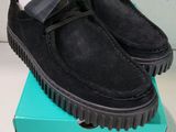 chaussures en daim noir ornées d'un nœud papillon, posées sur une boîte