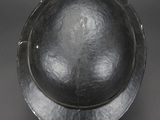 an old metal bowl with a metal rim on a gray surface
