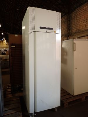 two refrigerators in a warehouse with a brick wall