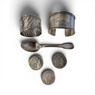 three silver cuff bracelets, a spoon, and a spoon rest on a white surface
