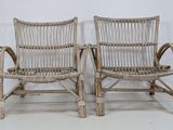 pair of wicker chairs with arms and backrests on a white background