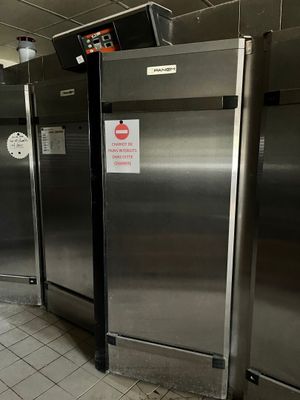Plusieurs réfrigérateurs en acier inoxydable sont alignés les uns à côté des autres dans une cuisine professionnelle