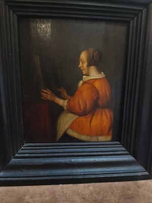 un vieux tableau représentant une femme tenant un miroir dans un cadre noir