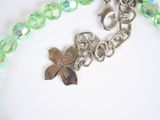 a green beaded bracelet with a flower charm on it