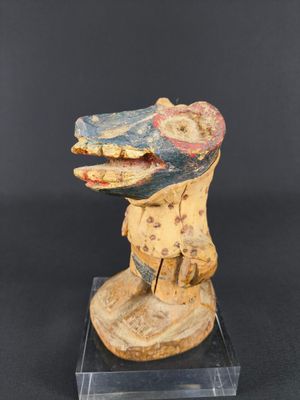 a wooden sculpture of a snake head on a clear base