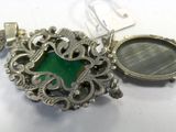 a close up of a silver locke with a green stone in it
