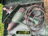 une boîte verte contenant des outils, posée dans l'herbe