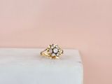 une bague de fiançailles en or ornée d'un motif floral, posée sur un bloc de marbre blanc