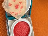 a bowl of red liquid next to a bowl of cream
