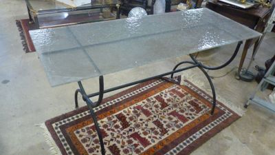 une table avec un plateau en verre et un tapis posé au sol