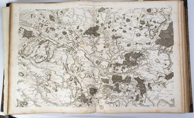 un vieux livre sur lequel figure une carte, posé sur une table