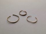 three pairs of gold hoop earrings sitting on top of a white surface