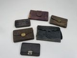 six petits sacs à main en cuir sont alignés sur une surface blanche