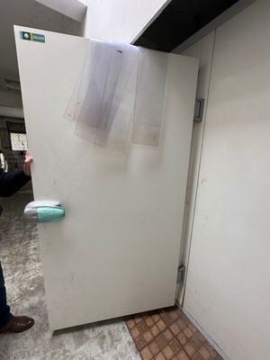 un homme debout à côté d'un réfrigérateur blanc dans une pièce