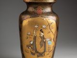 a gold vase with a picture of a man and a woman on it