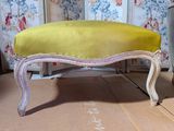 a yellow bench sitting on a wooden floor next to a blue chair