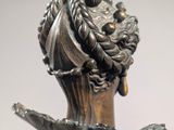 a bronze statue of a woman with a hat on her head
