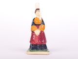une petite figurine de femme en robe rouge et bleue