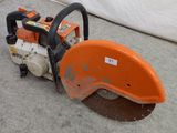 an orange and black chainsaw sitting on the floor next to a white sheet