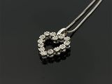 un pendentif en diamant en forme de cœur, suspendu à une chaîne, posé sur une surface noire