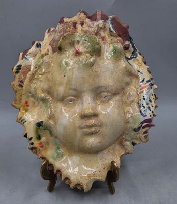 une sculpture en céramique représentant le visage d'une femme, posée sur un socle