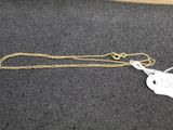 un collier en or muni d'une breloque, posé sur une table